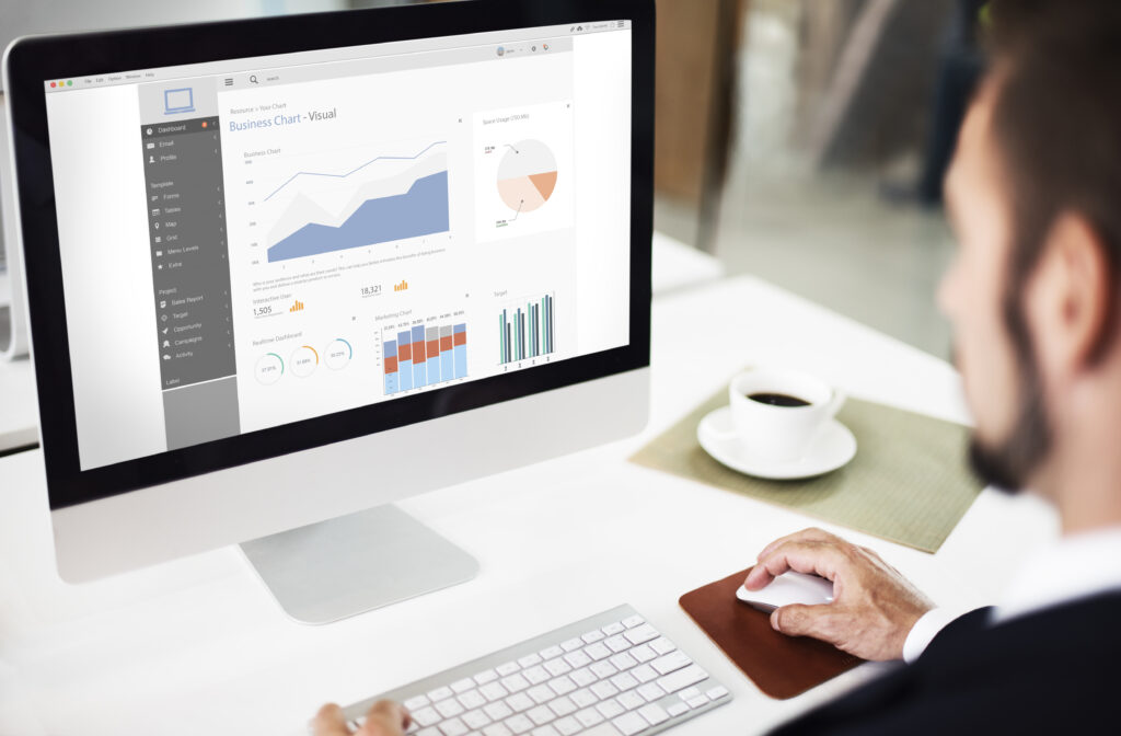 Business professional using best CRM software with reporting dashboard showing sales charts, marketing analytics, and real-time business data on desktop monitor