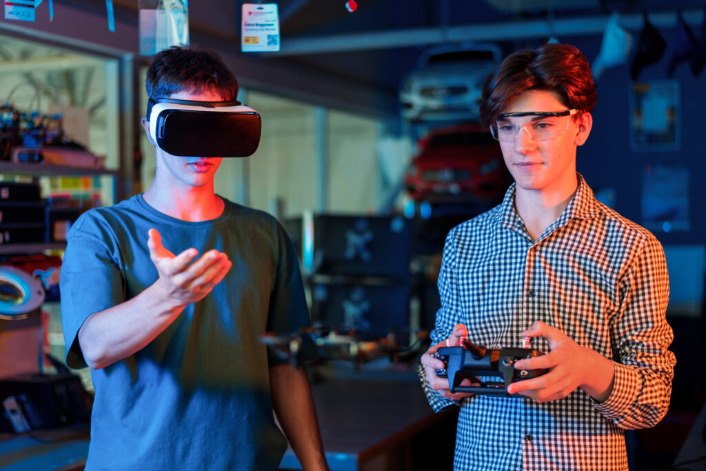 Two teenage students using a virtual reality headset and controller during a robotics experiment in a technology laboratory